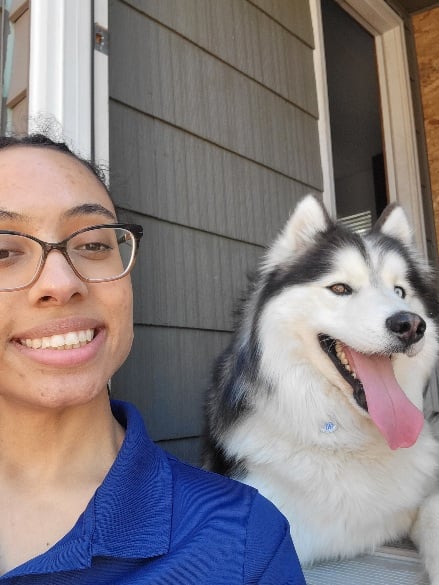 Woman sitting in front of her house with her malamute dog