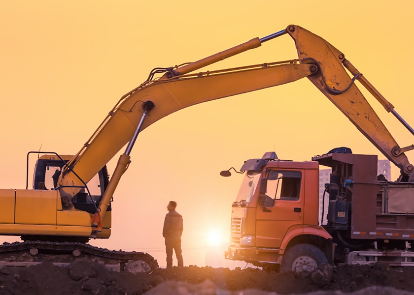 man standing by tractor at sunset