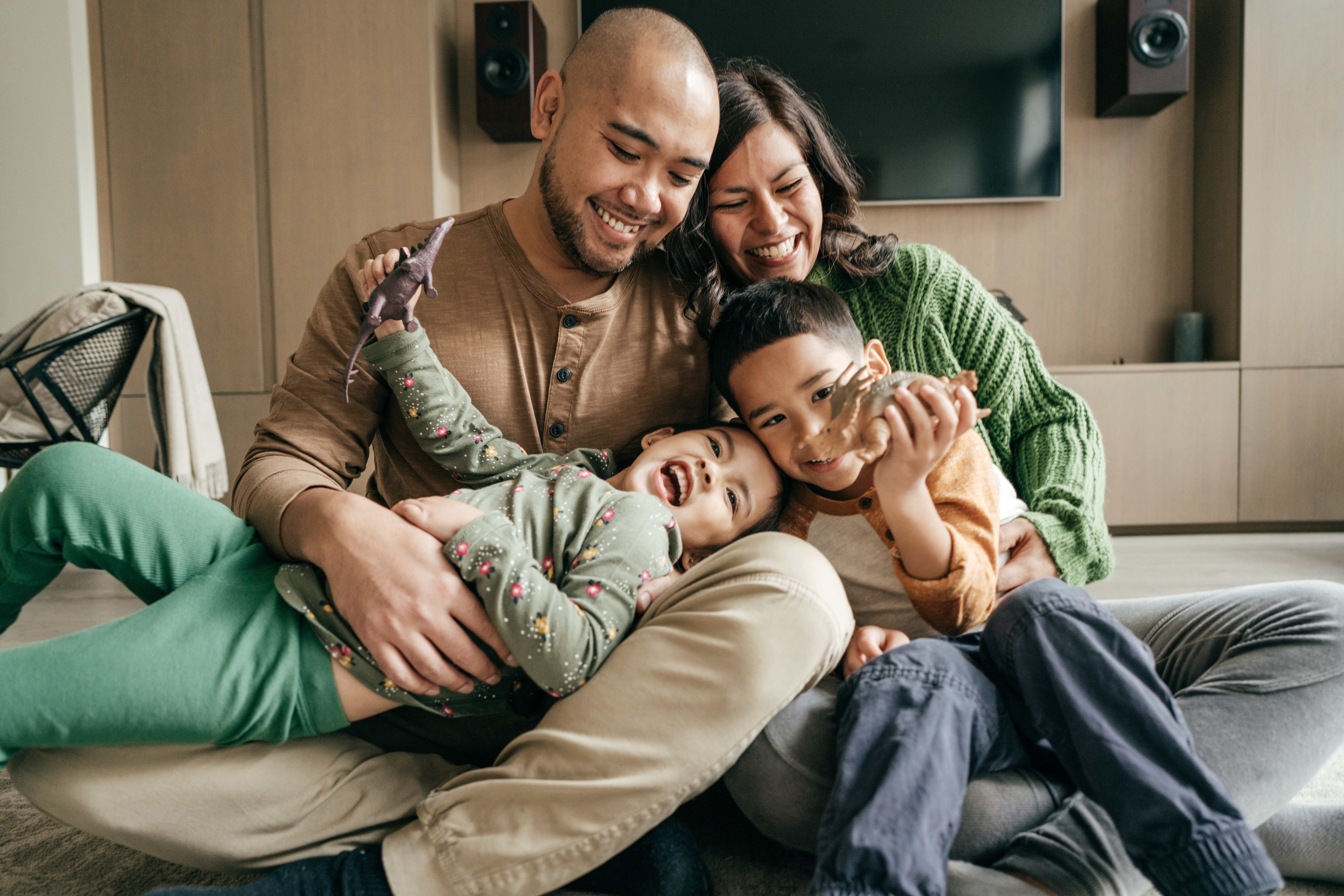 Dad, mom, daughter and son hugging and laughing in their living room